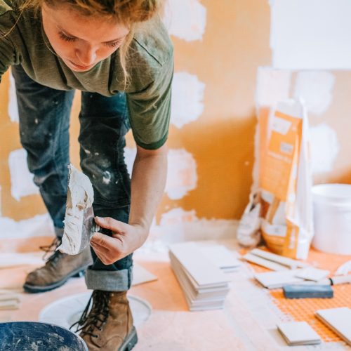 A Woman Worker Scooping Mud (Mortar) in a bathroom remodel