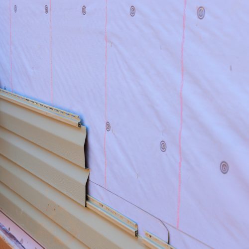 In process of installing vinyl siding on new home facade, a handyman installs vinyl PVC siding